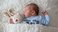 sleeping baby inside white blanket with teddy bear