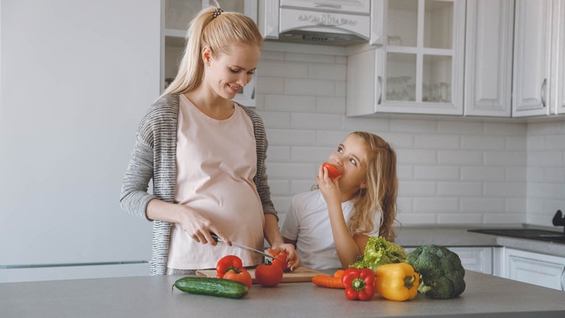 mom and daughter in kitchen eating vegetables
