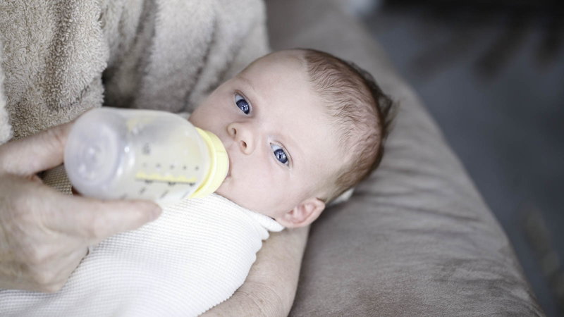 baby drinking bottle of breast milk