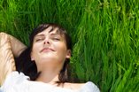A woman lies in the grass feeling happy with the benefits she's experienced staying sober.