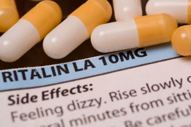 white and yellow ritalin pills next to prescription information