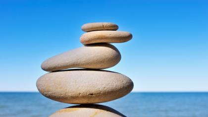 A stack of stones balances against a background of ocean and sky. 
