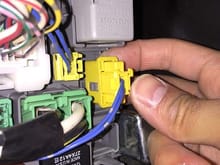 Grab under the yellow connector's outer shell and pull towards you while pushing on the center wire area.