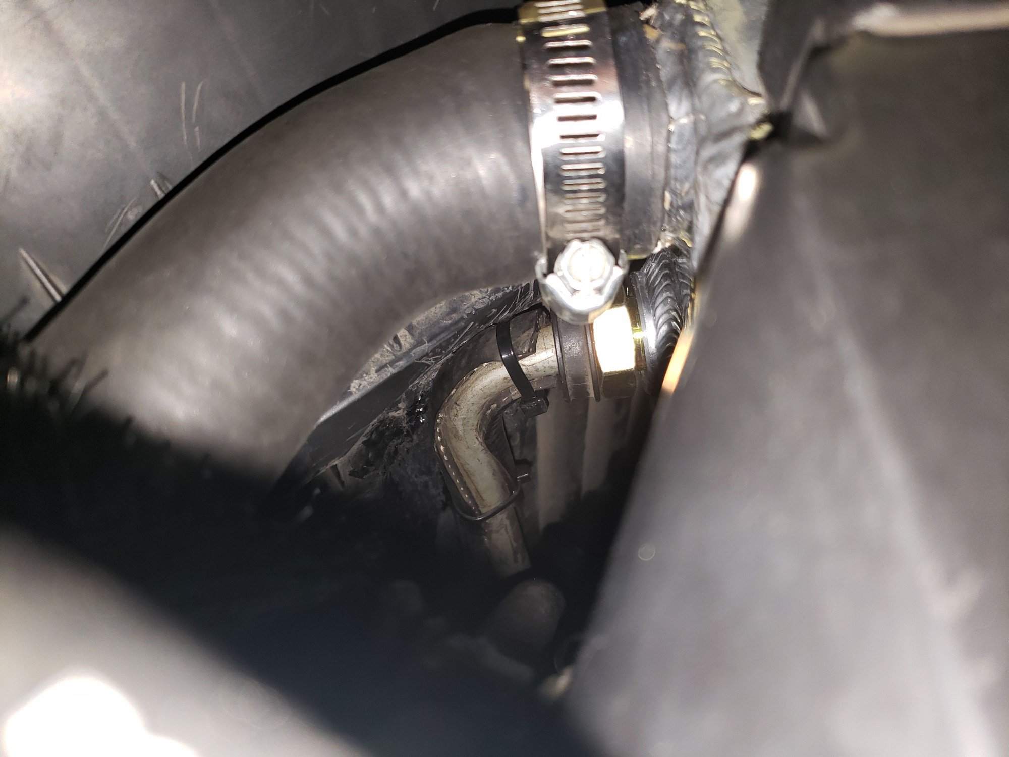 View of upper radiator hose on driver side looking down showing the upper oil-cooler line. If I had not made a dimple in the side of the air box, it would have rubbed against it. I added some scrap hose between it and the box.