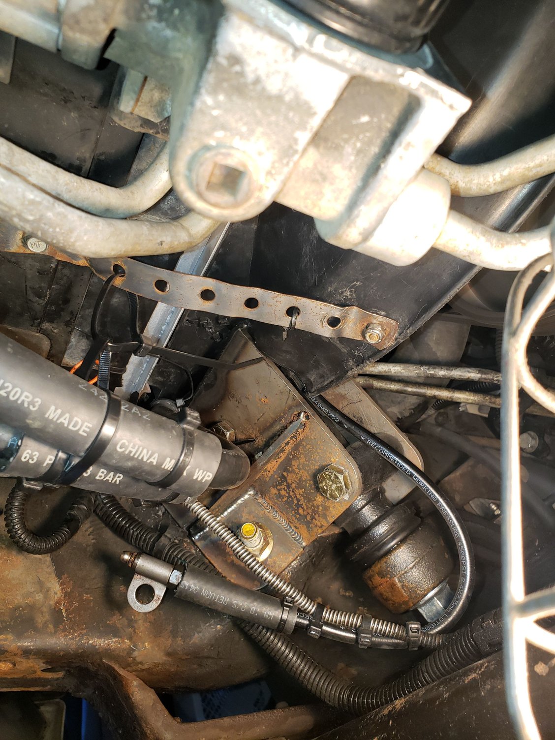 View from underneath showing the 1-ton idler arm upgrade. I had to route the supplemental transmission cooler lines between the top if it and the bottom of the fan shroud. I added lengths of scrap heater hose to protect the hoses from rubbing.