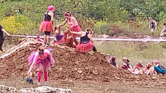 Daughter in purple top siitting at top of mud hill, pulling my wife to the top.
