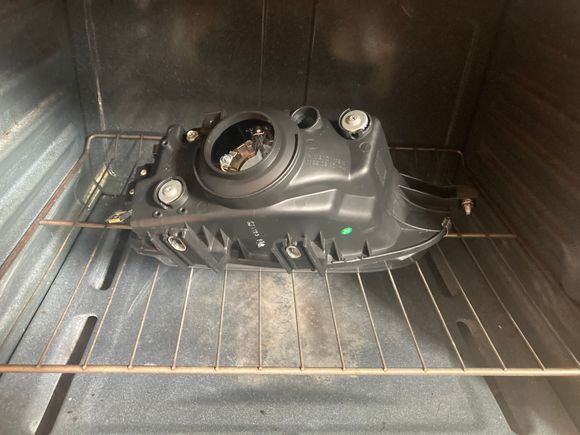 I heated the oven to 240F and then placed the housing in for 10 minutes. That got the adhesive softened up, but I put the housing back in for another 10 minutes and then I was able to separate the glass from the plastic.