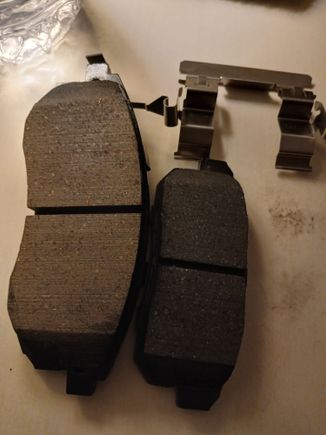 The front ASP815A ULTRA PERFORMANCE Akebono pads on left compared to the teeny weenie rear ACT1008 pads on right. The caliper bracket on top is for the front pads and is almost bigger than the rear PADS! 