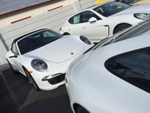 CW in foreground.  Two white Porsche’s in background.