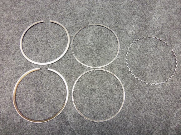 Original rings:  top left top compression ring, bottom left second compression ring, middle two thin oil control rings, right oil control rings expander.