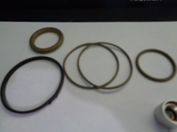 four green rubber o-rings and one black nylon piston ring