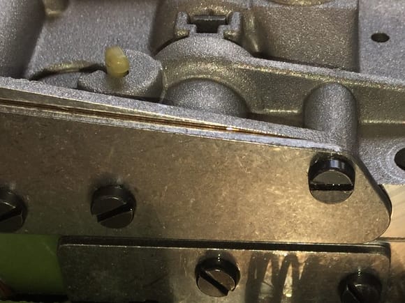 The whitish/yellow plastic piece is the underside of the 'modulating pressure valve.' Note where the raised casting it sits in intersects the raised casting of the brake shift shut off valve bore to the right. This is where the passage is.