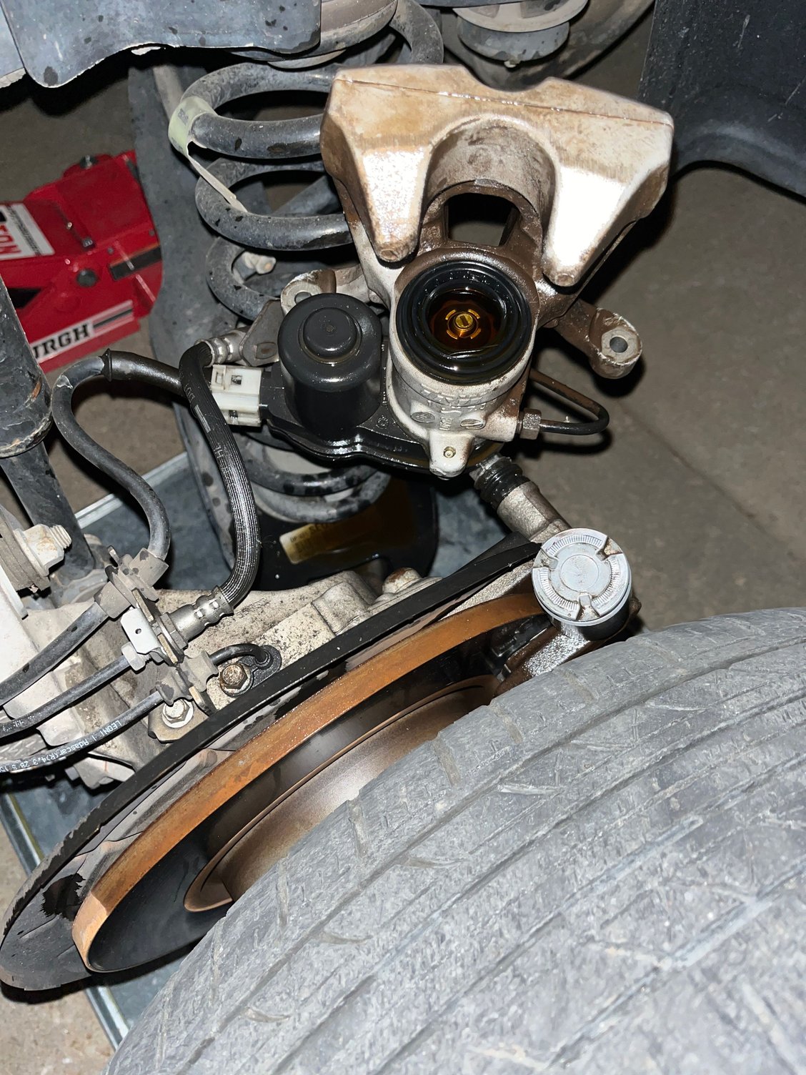 Shows the caliper with the rubber boot missing the piston which is sitting just above the tire.