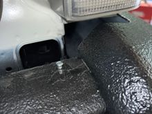 The lip of the bumper trip is pulled over this self tapping screw for a little added security