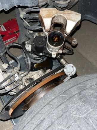 Shows the caliper with the rubber boot missing the piston which is sitting just above the tire.