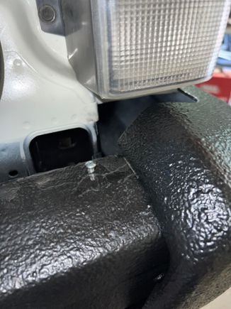 The lip of the bumper trip is pulled over this self tapping screw for a little added security