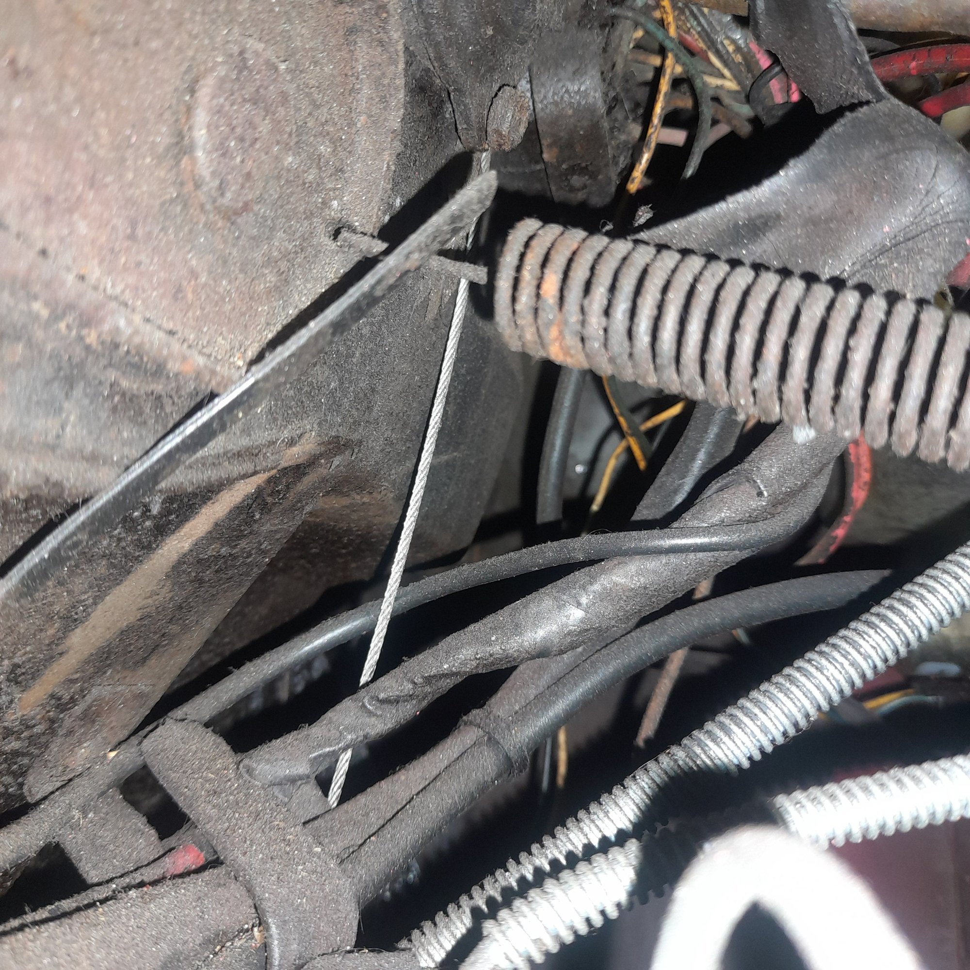 What a hard thing to get a photo of! Hope this helps. Directly below where the rod comes through the firewall. 