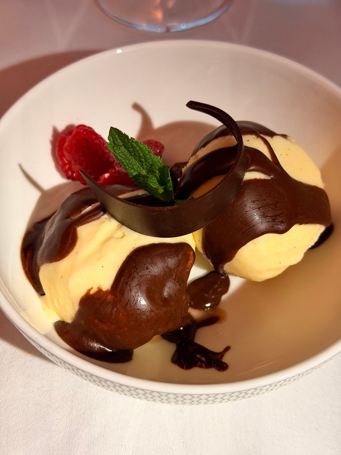 Homemade vanilla ice cream, raspberries, chocolate sauce, chocolate shavings