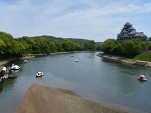 The castle from the footbride across the Asahi  river. Boats for rent just outside the garden including peach shaped boats. 