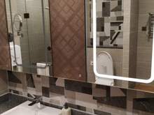 Large shower room with lit vanity mirrors and a set of vanity items (Chinese mouthwash, toothbrush/paste, q-tips, shower cap).