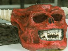 Intermittent rain resulted in some Correfoc figures being held back in storage coz they were made of materials that could not stand water. Shown here through a window at the Barceloneta district museum housing past Correfoc items, a fierce fanged mask.