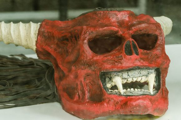 Intermittent rain resulted in some Correfoc figures being held back in storage coz they were made of materials that could not stand water. Shown here through a window at the Barceloneta district museum housing past Correfoc items, a fierce fanged mask.
