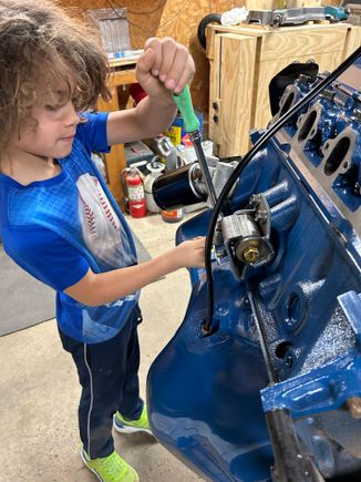 So we jumped to the other side I took the manifold back off and then cracked the motor bounce loose and then let him take them off. He’s still at that age where he really likes to do the ratchet and then I handed him the hammer and I held the center punchand let him knock the freeze plugs out of this side. Yes, under my breath I was praying he didn’t slip off and hit my hand, but he did great of course he knocked one into the block also and we had to dig it out, but he thought it was fun getting