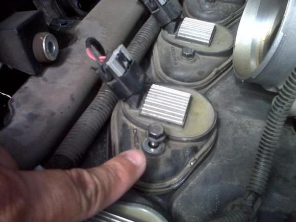 There is a single 10 mm holding in each Delphi module. Once removed, the entire assembly slides up and off of the spark plug. On the front most cylinder, the wiring harness has to be moved to allow removal of the module. Remove the cap on the wireway cover and there are 2 plastic fasteners holding it in place. These can be rotated and screwed down through the slot in the bottom of the wireway using a screw driver. The cover can be seen in the previous picture.