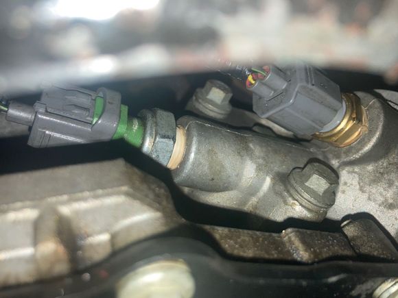 Engine Oil Temp Sensor is the one with the yellow wire. Oil pressure sensor is the one with a single black/green wire.