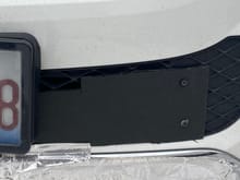 Black 1/4” foam board slipped behind license plate and two screws used through the plastic . 