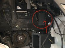 Circled is the electrical ground box mentioned earlier.  The cables running to it are in the way of the motor mount, so it has to get sung out of the way along with the washer reservoir.  The arrow points to the single nut (10mm) that holds it in place.  That nut/bolt is the connection to ground for a bunch of RF circuits -- headlight, fog light, parking light, ride height sensor, leveling control for the headlights if your car is equipped. Be sure to inspect, reconnect, & test before button-up.