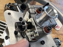 I'm pointing to the single hole I drilled in the factory throttle stop bracket.