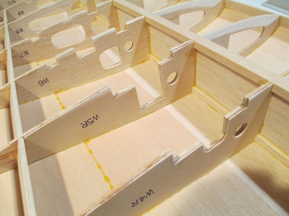 Time to epoxy one of the 1/2" x 3/4" x 6-3/4" basswood landing gear rail into place.  The rail is supported by ribs W4, W5 and W6.  These ribs are reinforced by epoxying birch plywood to the sides of each ribs.