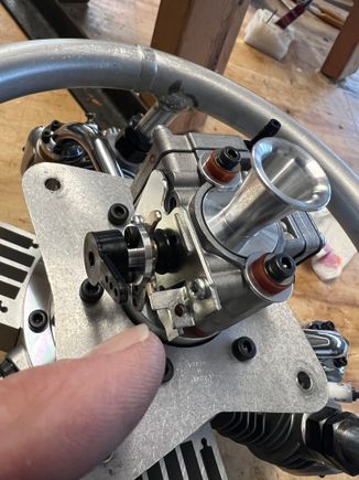 I'm pointing to the single hole I drilled in the factory throttle stop bracket.