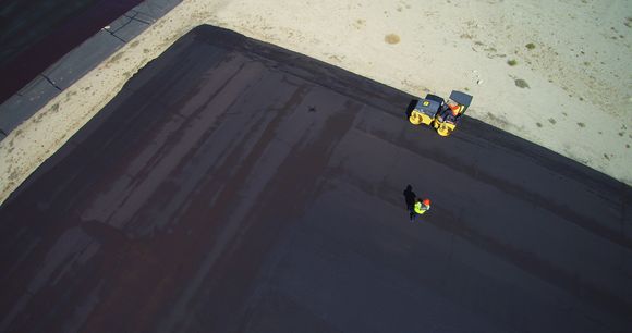   Dirk made a very good suggestion, after the first coat, complete surface rolled with a steel 5 ton roller.