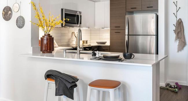 Apartment Kitchen with Stainless Steel Appliances, quartz counters and wood floors.